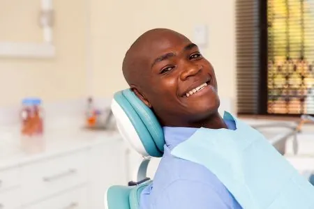 A man smiles while sitting back in a dentist chair, as though waiting for his same-day crowns to be milled in the office.
