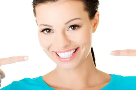 Woman with beautiful smile pointing at her teeth